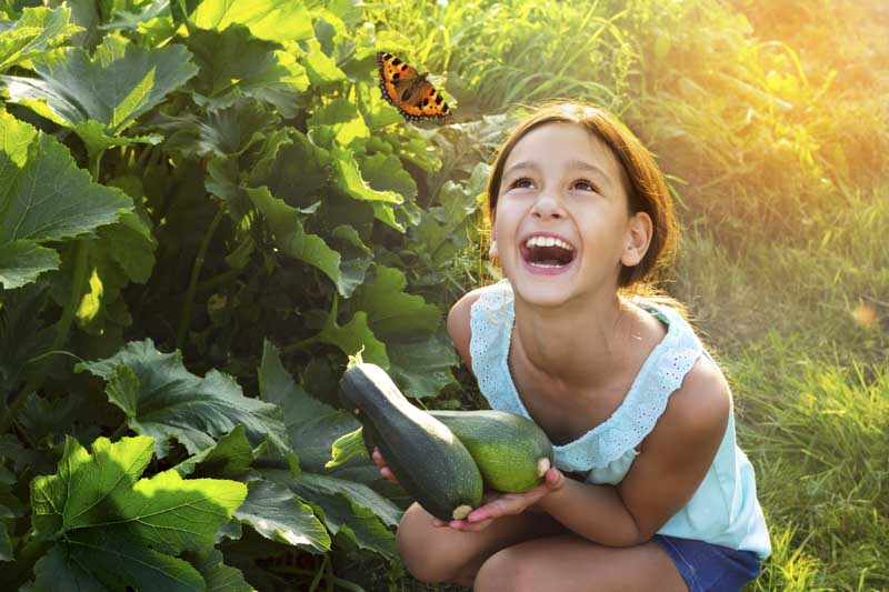 Young girl smiling at a butterfly floating above her