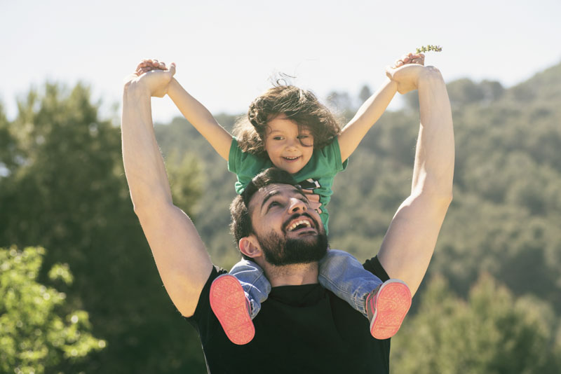 Father holding his son on his shoulders with his arms in the air