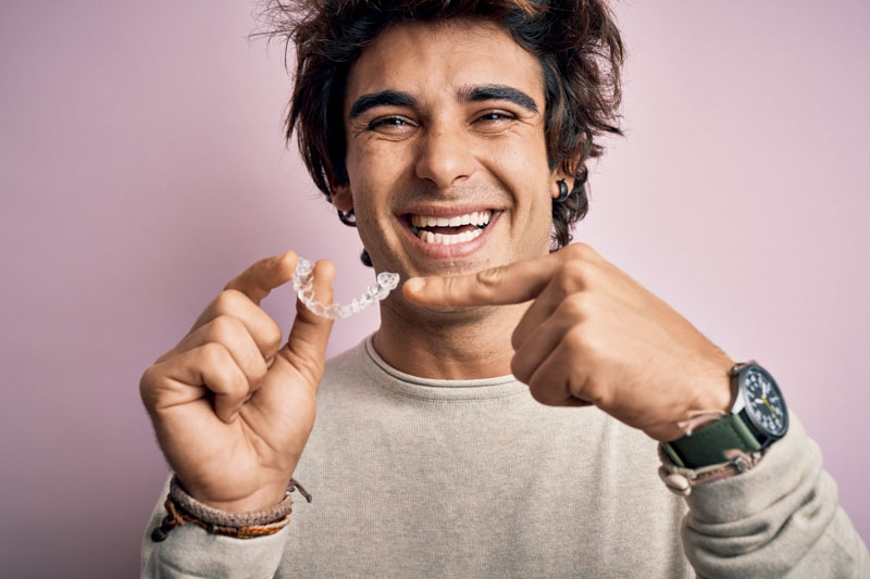 Adult man pointing and smiling at his clear aligner