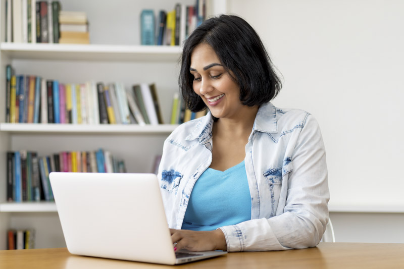 Woman wearing a jean jacket searching on a laptop